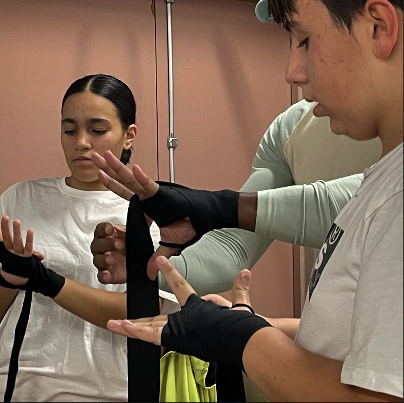 Deux jeunes du club apprennent à mettre leurs bandes de boxe avant le cours