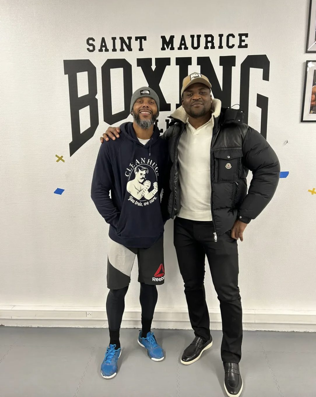 Francis Ngannou et « Tonton » Christian Mpumbu, head coach du Boxing Club Saint-Maurice, devant le mur du club
